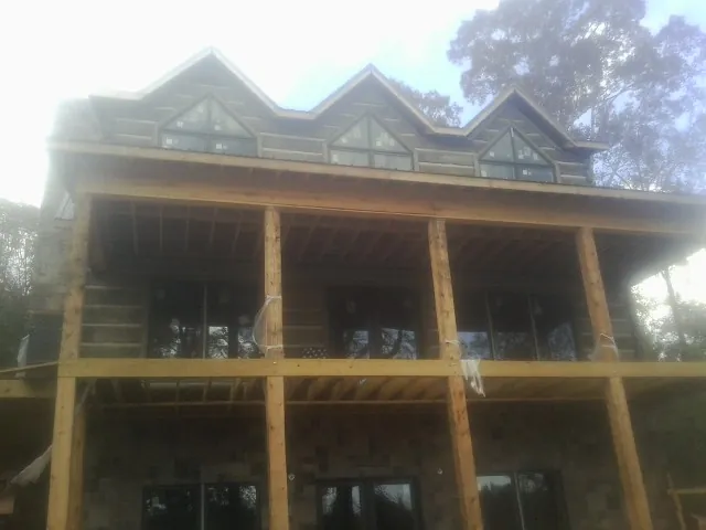 Dormers and porch framing on a large log home under construction — Roof Coating work by our crew in Geneva